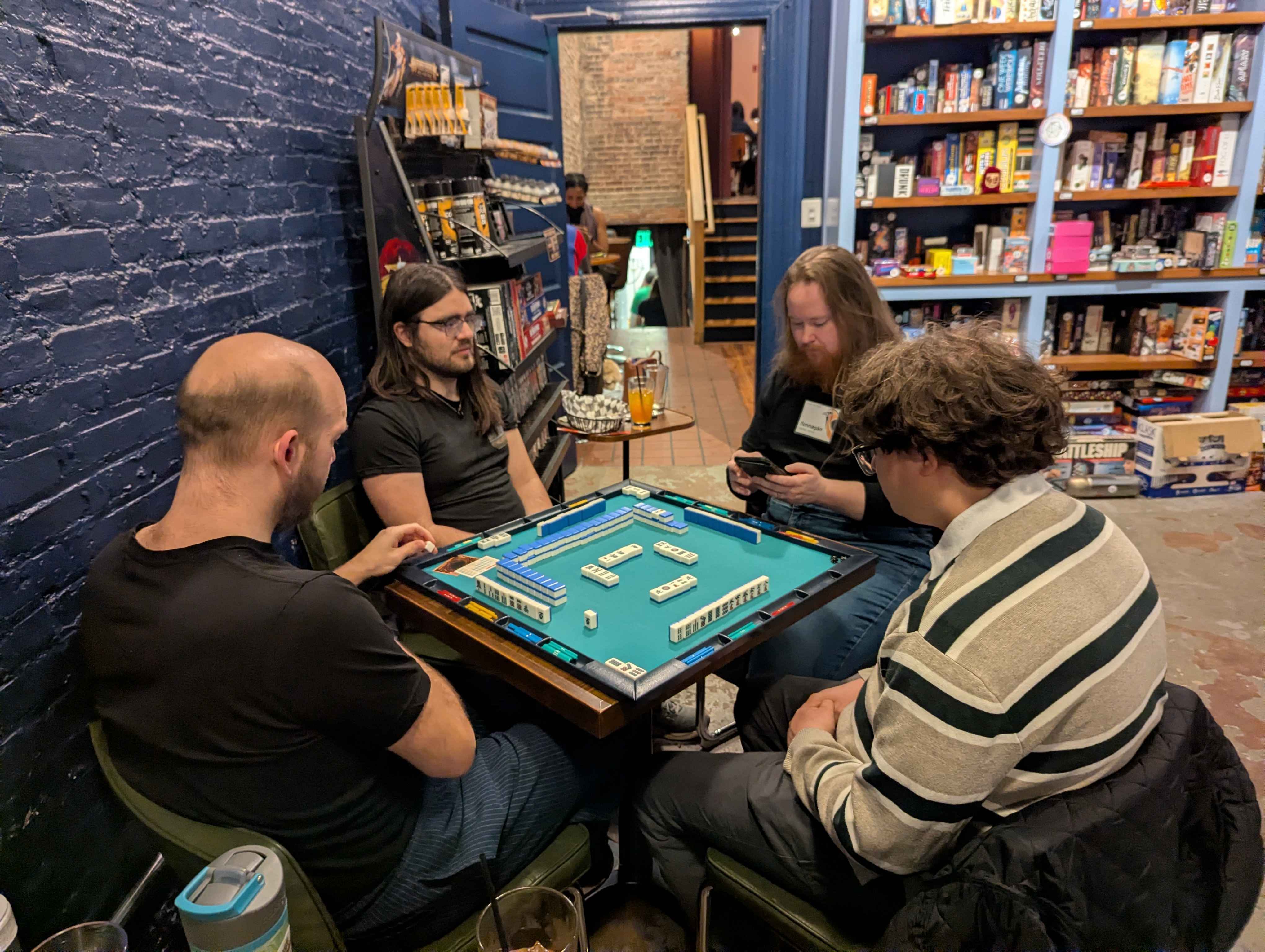 Four players focused on a riichi mahjong game at No Land Beyond in Baltimore, MD