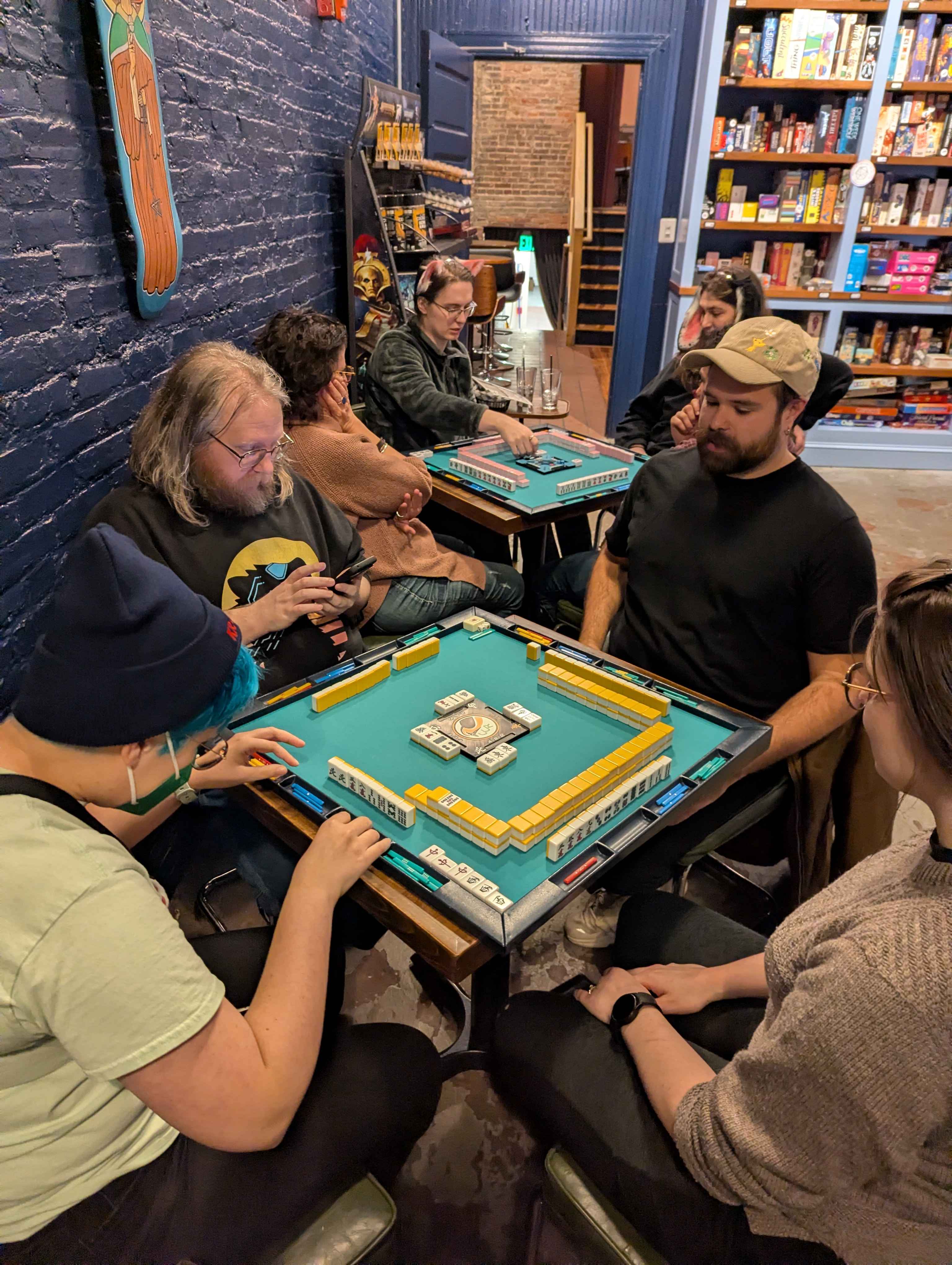 Charm City Riichi members playing multiple simultaneous mahjong games at No Land Beyond in Baltimore, MD