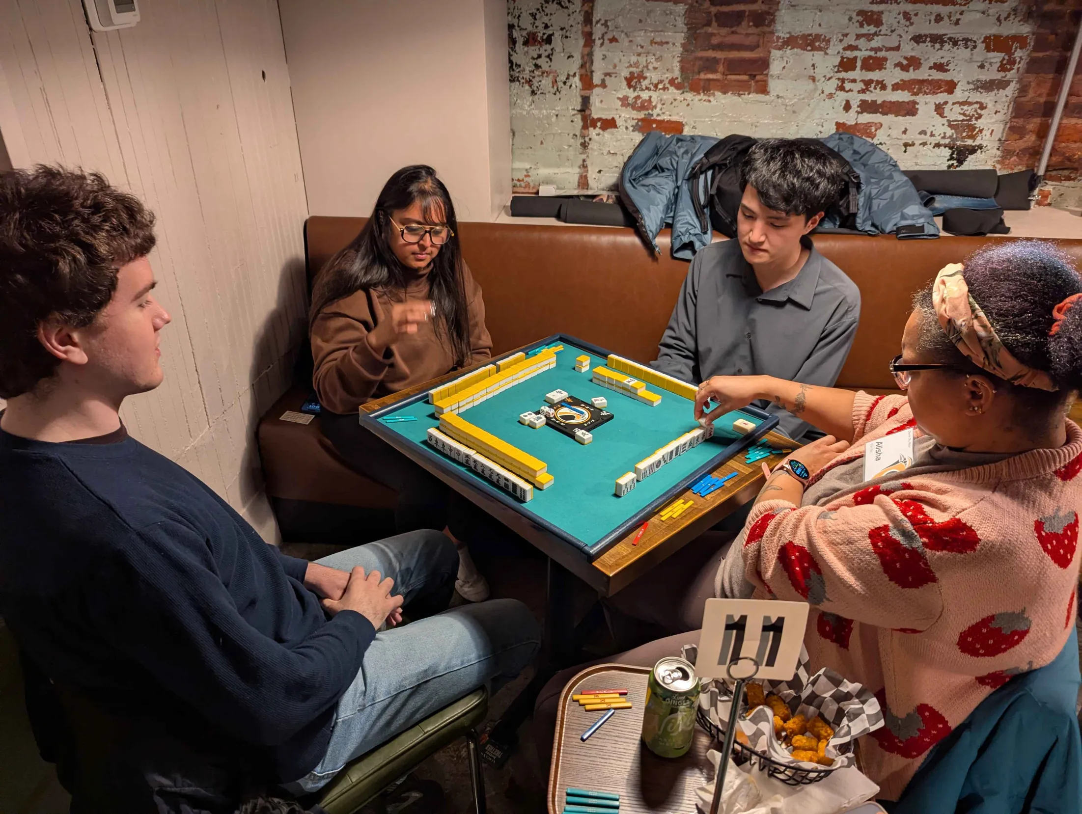 Four Charm City Riichi members playing mahjong together at a weekly meetup